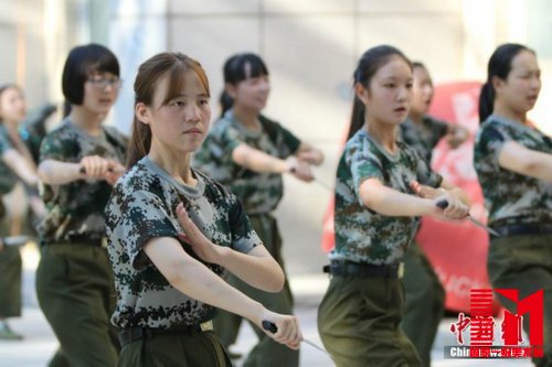 操场上,姑娘们手中紧握约15厘米长的橡胶制“匕首”,“哈!”伴随着一声清亮的口号,她们右脚原地用力下踏,左脚向右大跨弓步的同时迅速向左转身,左臂向上化掌格挡在胸前,持匕首的右手挥刀猛力向前刺出。129人的队列动作整齐划一,她们昂头收颌,目视前方,眼神坚定,英气十足。
